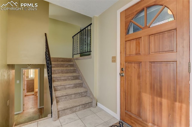 foyer featuring stairway, baseboards, and light tile patterned floors