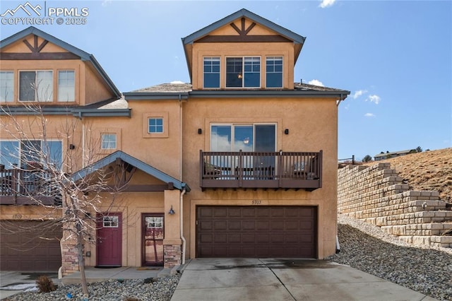 view of front of property with driveway, a balcony, an attached garage, and stucco siding