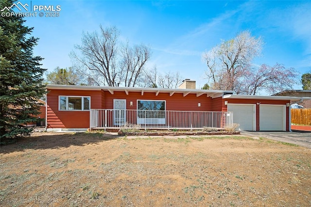 mid-century modern home with aphalt driveway, covered porch, a garage, and a chimney