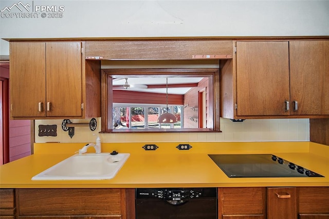 kitchen featuring tasteful backsplash, a sink, light countertops, brown cabinets, and black appliances