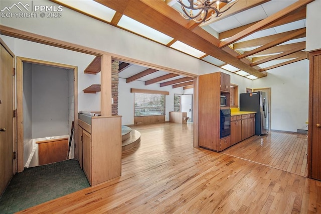 kitchen with a chandelier, light wood-type flooring, appliances with stainless steel finishes, and lofted ceiling with beams