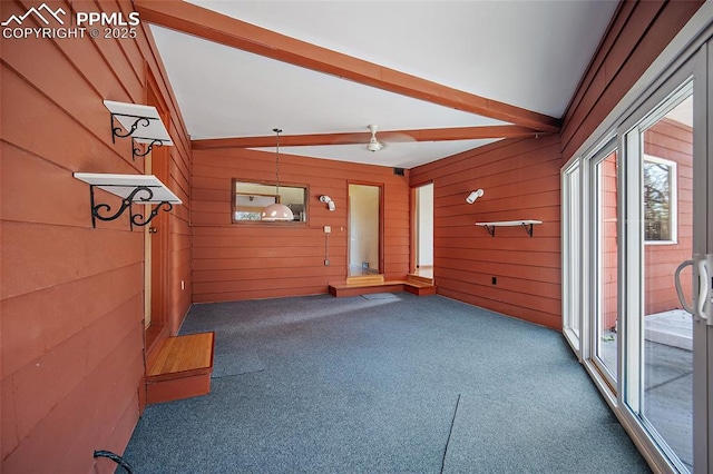 interior space with wooden walls, lofted ceiling with beams, and a healthy amount of sunlight