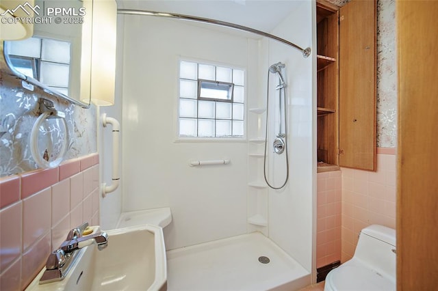 full bathroom with a sink, tile walls, toilet, and a stall shower