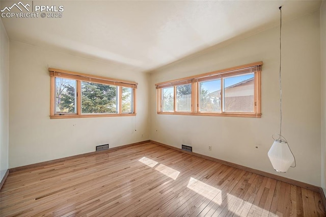 empty room with light wood-style flooring, visible vents, baseboards, and plenty of natural light