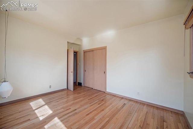 unfurnished bedroom with a closet, light wood-style floors, and baseboards
