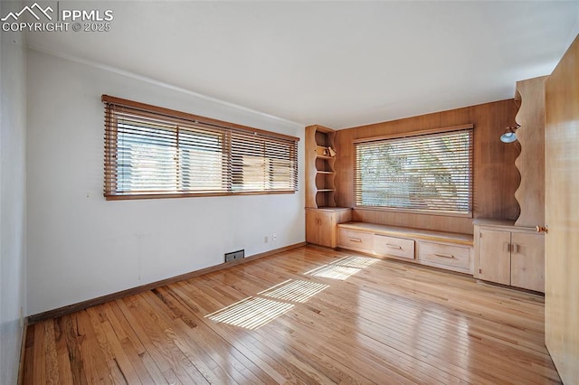 unfurnished room with light wood-style flooring, crown molding, and baseboards