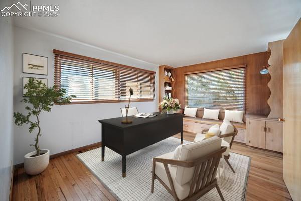 office space with wood walls, plenty of natural light, light wood-style flooring, and baseboards