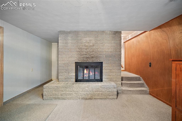 unfurnished living room featuring wooden walls, a fireplace, baseboards, and carpet floors