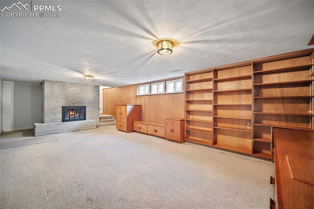 interior space with wood walls, a fireplace, and carpet