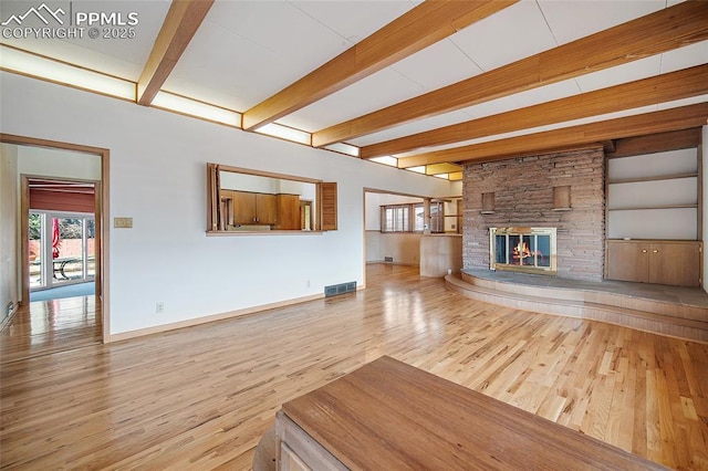 unfurnished living room featuring visible vents, beam ceiling, and wood finished floors