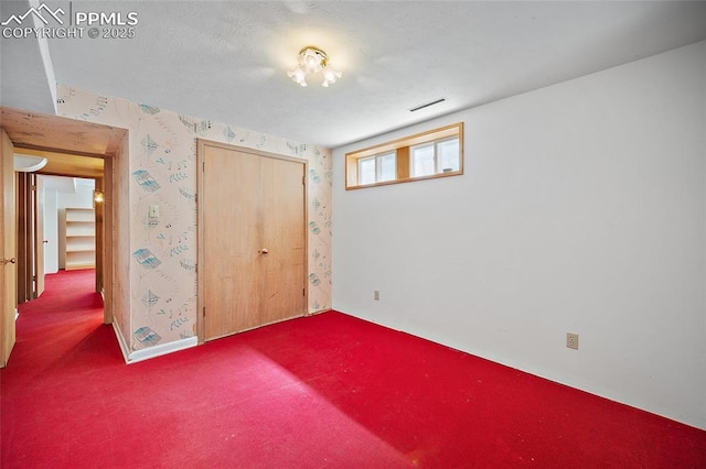 unfurnished bedroom featuring wallpapered walls, carpet flooring, a closet, and visible vents
