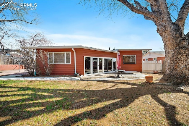 rear view of house featuring a patio, a yard, and fence