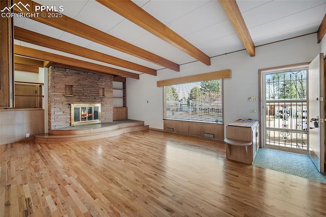 unfurnished living room featuring a fireplace, beamed ceiling, and wood finished floors