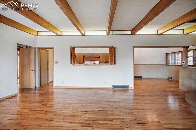 unfurnished living room with visible vents, beam ceiling, and wood finished floors