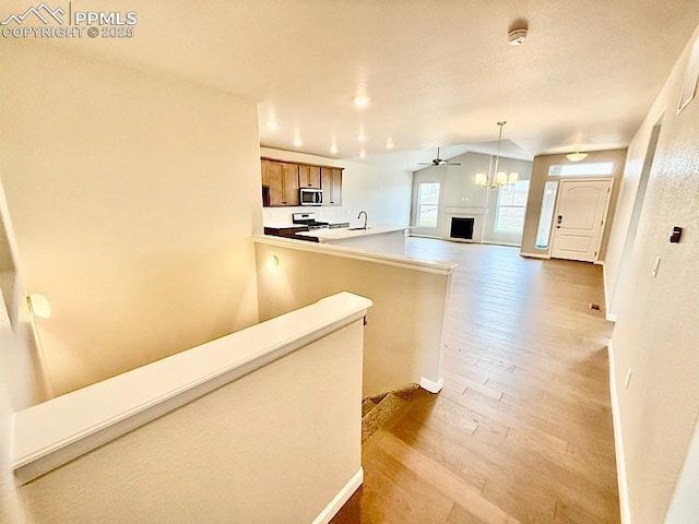 9455 Jollity Pt, Colorado Springs, CO 80924 - kitchen featuring stainless steel microwave, wood finished floors, brown cabinetry, open floor plan, and a peninsula