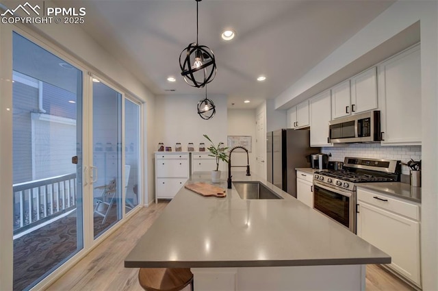 kitchen with stainless steel appliances, tasteful backsplash, a sink, and white cabinetry