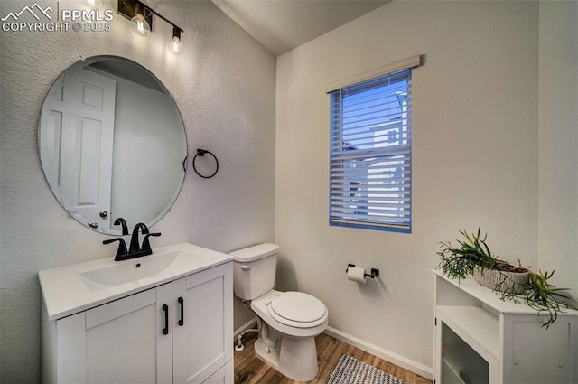 bathroom with toilet, baseboards, wood finished floors, and vanity