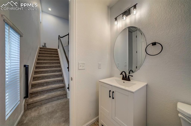 bathroom featuring a textured wall, vanity, and toilet