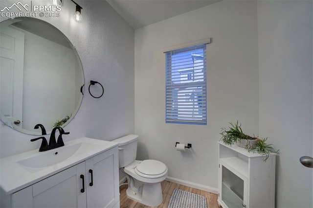 half bathroom with toilet, baseboards, wood finished floors, and vanity