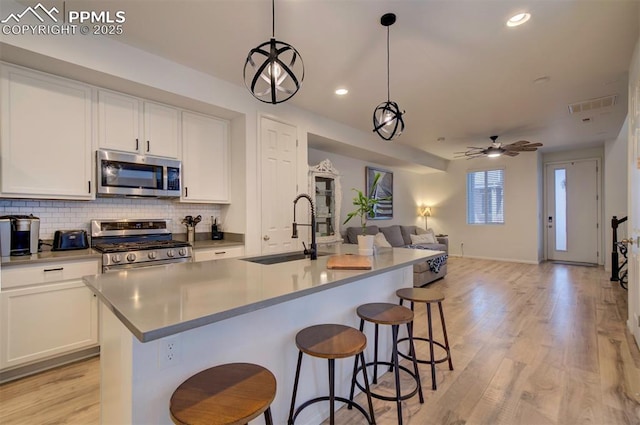 kitchen with stainless steel appliances, visible vents, backsplash, open floor plan, and a sink