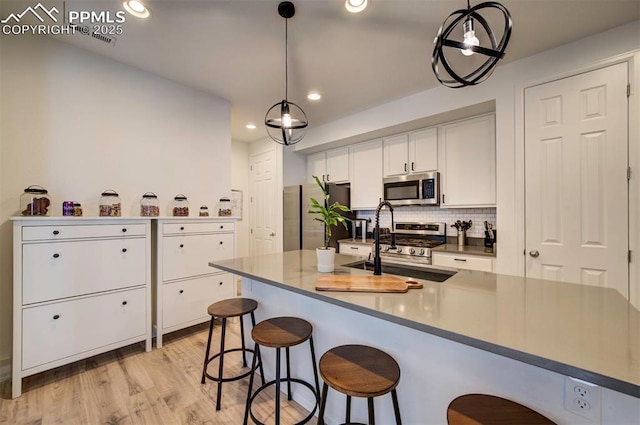 kitchen featuring tasteful backsplash, light wood-style flooring, appliances with stainless steel finishes, white cabinetry, and a sink