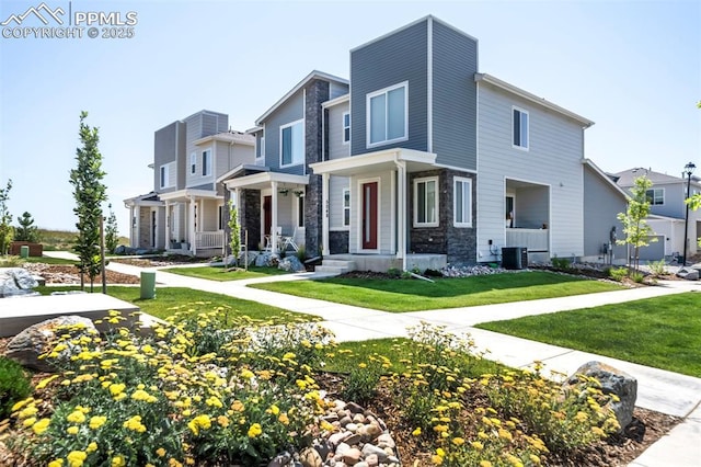 view of front facade with central air condition unit, stone siding, a residential view, and a front lawn