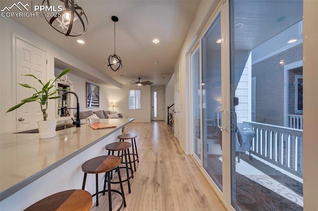 kitchen featuring a breakfast bar area, recessed lighting, open floor plan, hanging light fixtures, and light wood finished floors