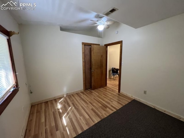 unfurnished bedroom featuring a ceiling fan, visible vents, baseboards, and wood finished floors