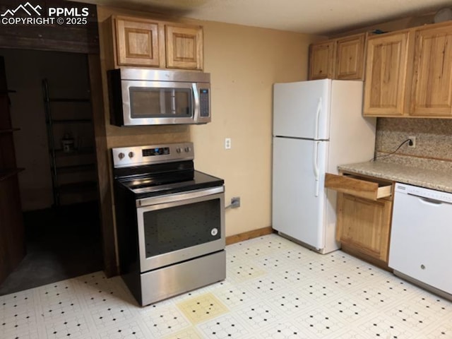 kitchen with light floors, light countertops, decorative backsplash, appliances with stainless steel finishes, and baseboards