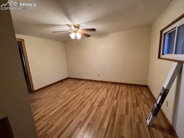 spare room featuring a ceiling fan, baseboards, and wood finished floors