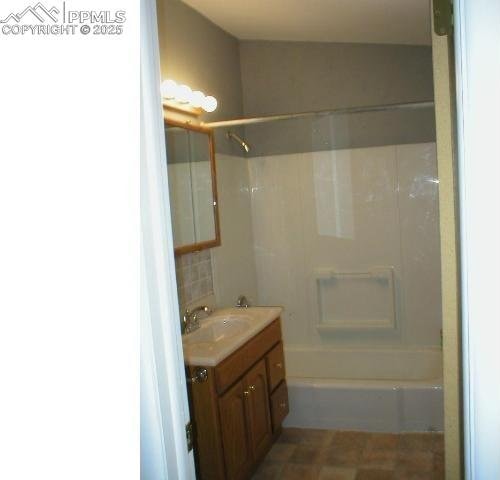 bathroom featuring  shower combination, decorative backsplash, and vanity