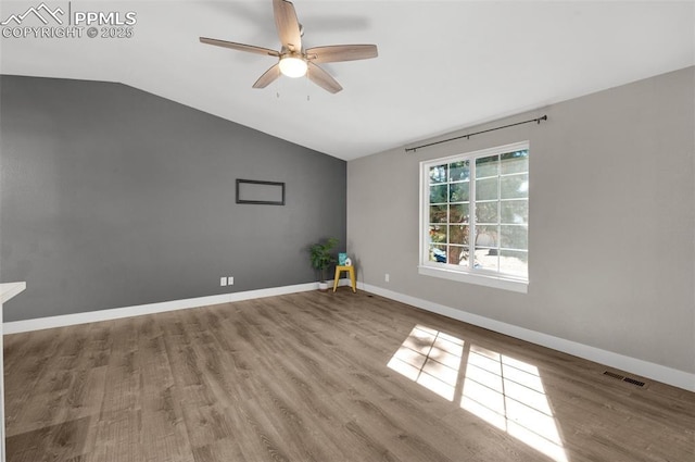 empty room featuring lofted ceiling, ceiling fan, wood finished floors, visible vents, and baseboards