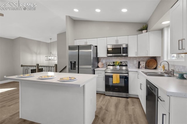 kitchen with a center island, stainless steel appliances, lofted ceiling, light countertops, and a sink