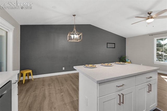 kitchen featuring white cabinets, vaulted ceiling, light countertops, light wood-style floors, and dishwasher