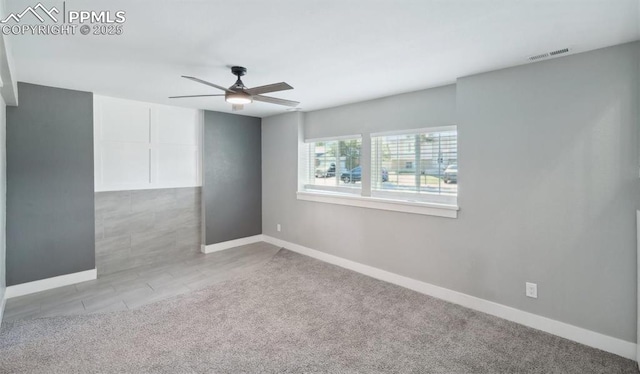 carpeted spare room with a ceiling fan, visible vents, and baseboards