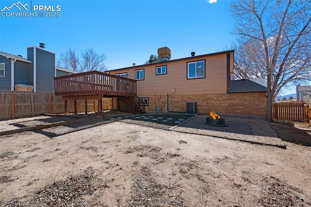 rear view of house featuring brick siding, fence private yard, a fire pit, a wooden deck, and stairs