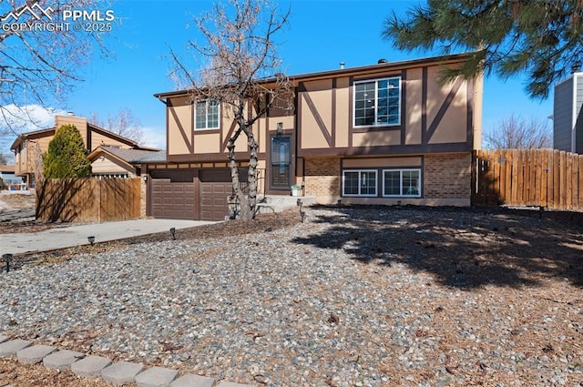 view of front of home with a garage, brick siding, fence, and stucco siding