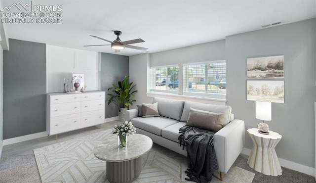 living area with baseboards, visible vents, and a ceiling fan