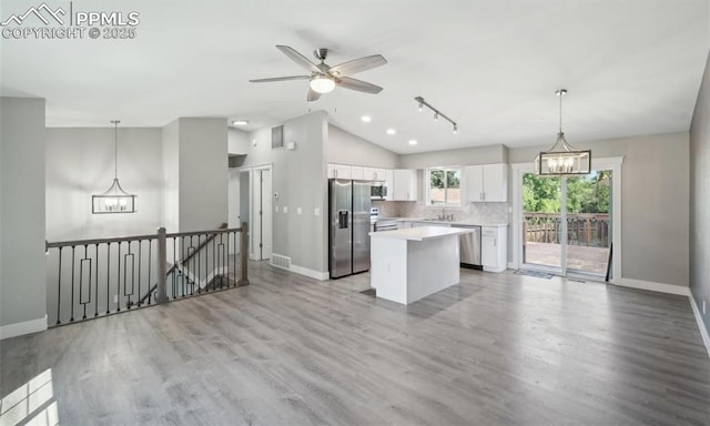 kitchen featuring a center island, light countertops, decorative backsplash, appliances with stainless steel finishes, and white cabinetry