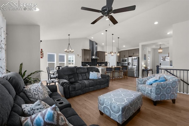 living area with recessed lighting, light wood-type flooring, ceiling fan with notable chandelier, and vaulted ceiling