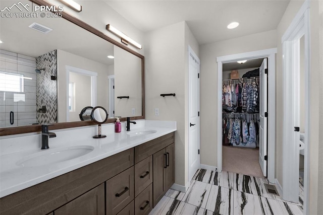 bathroom featuring double vanity, visible vents, a stall shower, and a sink