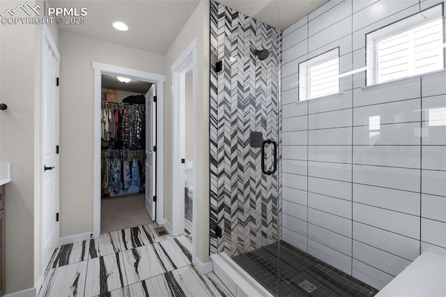 full bathroom with a walk in closet, baseboards, toilet, and a shower stall