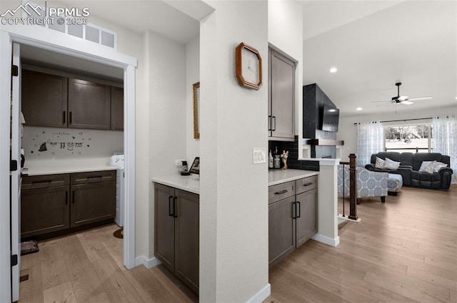 kitchen featuring a ceiling fan, light wood finished floors, decorative backsplash, light countertops, and open floor plan