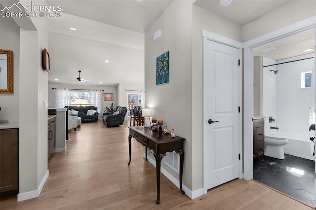 hallway with light wood finished floors, recessed lighting, and baseboards