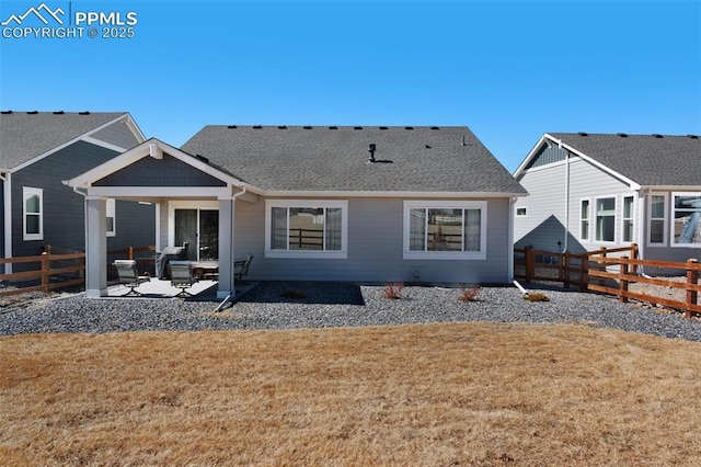 rear view of house featuring a patio, a lawn, roof with shingles, and a fenced backyard