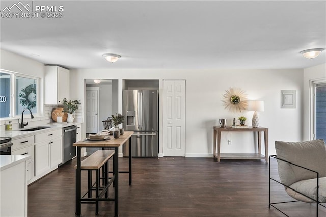 kitchen featuring stainless steel appliances, light countertops, dark wood-type flooring, white cabinetry, and a sink