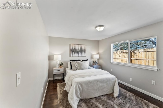 bedroom featuring wood finished floors, visible vents, and baseboards