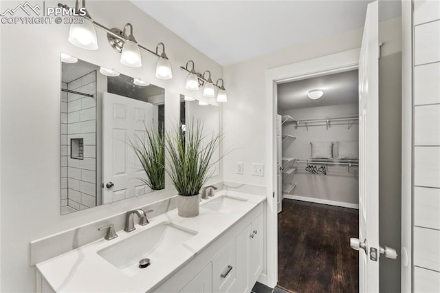 bathroom with double vanity, a spacious closet, a sink, and wood finished floors