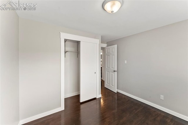 unfurnished bedroom with a closet, baseboards, and wood finished floors