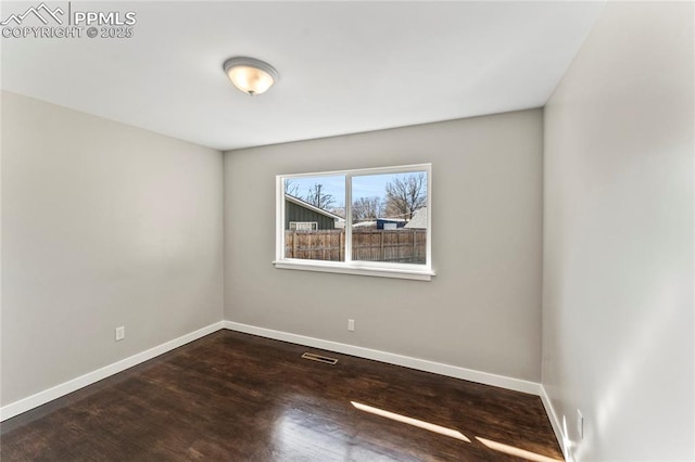 spare room featuring baseboards, visible vents, and wood finished floors